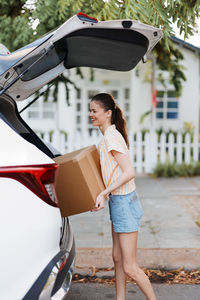 Rear view of woman using mobile phone while standing in car