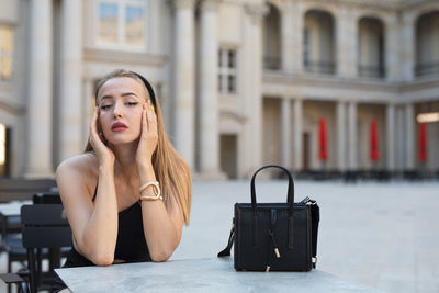 Portrait of young woman sitting in city