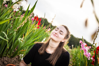 Portrait of beautiful young woman against white flowering plants