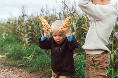 Children in corn field having fun, making horns