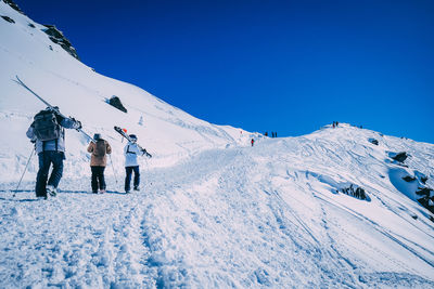 People on snowcapped mountain against clear blue sky