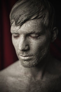 Close-up of shirtless man with mud facial mask
