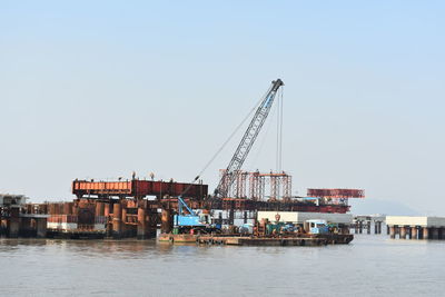 Cranes at commercial dock against clear sky