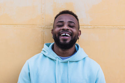 Portrait of smiling man standing against wall