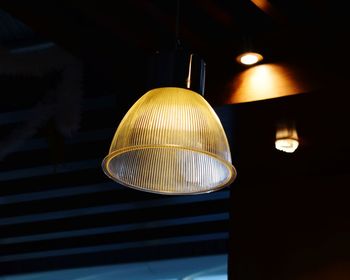Low angle view of illuminated pendant light in darkroom