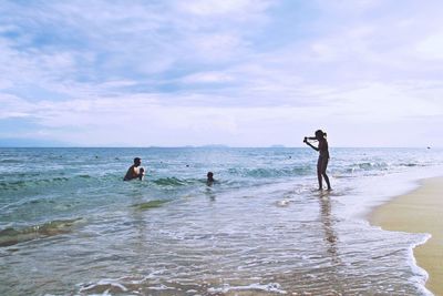 People at beach against sky