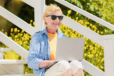 Senior authentic woman using laptop for distance learning education outdoors