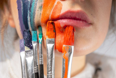 Close-up of young woman painting face and lips