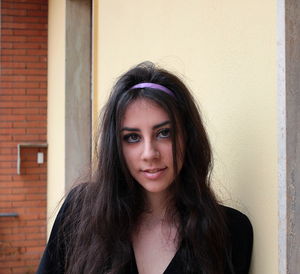 Portrait of smiling young woman against wall