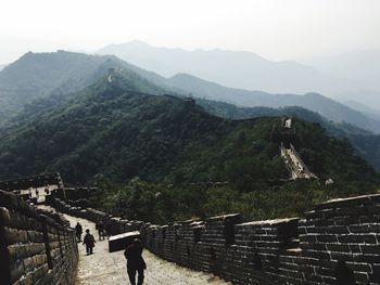 People walking on great wall of china against mountains