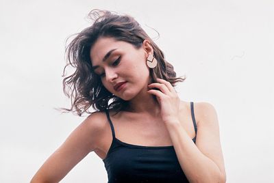 Woman looking down while standing against white background