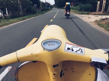 Close-up of yellow motor scooter on road
