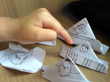 High angle view of hand holding paper with text on table