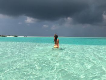 Woman standing in sea against sky