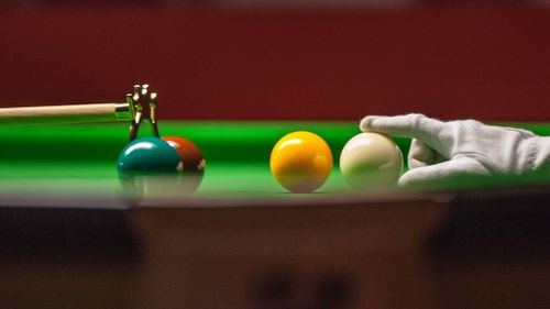 Close-up of hand adjusting ball on pool table