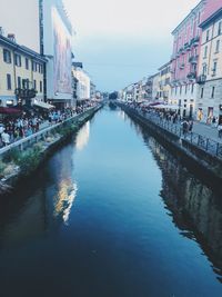 Canal amidst buildings in city against sky