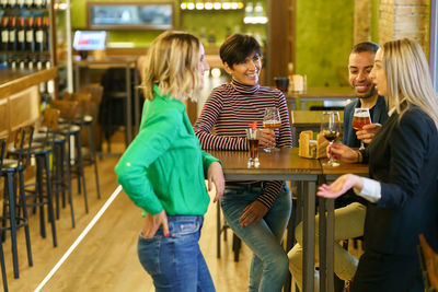 Rear view of young woman using mobile phone while standing in cafe