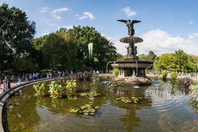 People by bethesda terrace and fountain at central park against sky