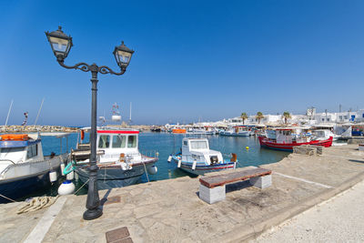 Boats moored at harbor against clear blue sky