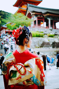 Rear view of woman in kimono standing against shrine