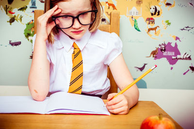 Tensed girl with book on desk in school