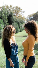 Side view of young caucasian female friends smiling while having a conversation in park looking at each other