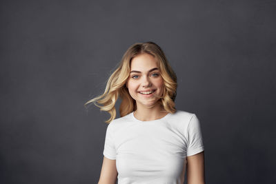 Portrait of smiling young woman against black background