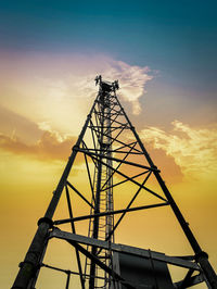 Low angle view of silhouette communications tower against sky during sunset