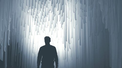 Silhouette man standing against illuminated abstract background