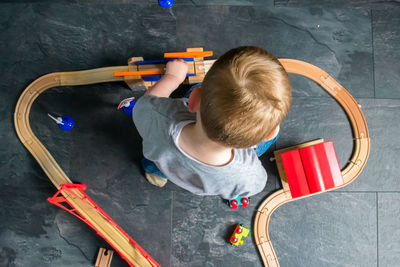 High angle view of boy playing with miniature train at home