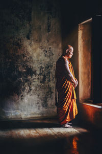 Full length of monk standing in darkroom