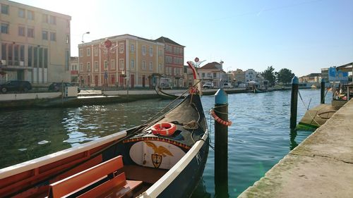 Boats in canal by buildings against sky in city