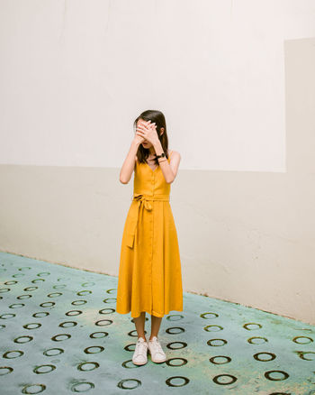 Full length of young woman standing against wall