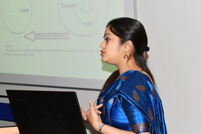 Side view of young woman wearing blue sari having business meeting