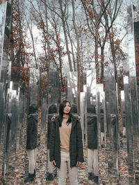 Portrait of young woman standing by bare trees during winter