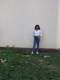 Portrait of young woman standing against wall