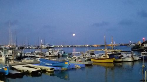 Boats moored at harbor against sky