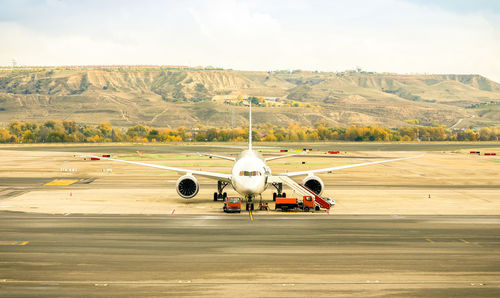 Airplane on airport runway against sky