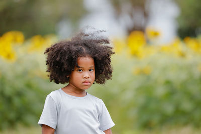 Portrait of cute girl standing on yellow flowering plants