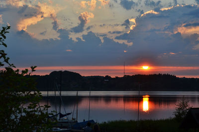 Scenic view of lake against cloudy sky at sunset