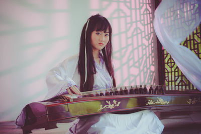 Young woman playing musical instrument at home