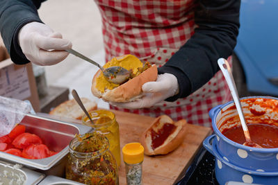 Midsection of person preparing hot dog at market stall