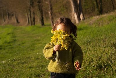 Girl holding flowers while standing on field