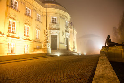 Man statue at illuminated temple against sky