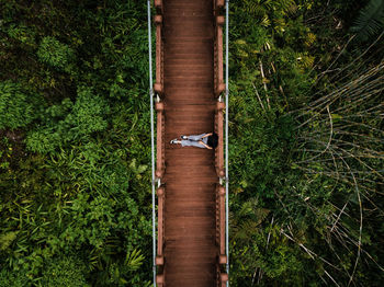 Aerial view of woman sitting on footbridge in forest