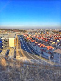 High angle view of road amidst buildings against clear blue sky
