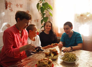 An elderly woman in bright clothes sets the table, arranges homemade cakes, prepares 