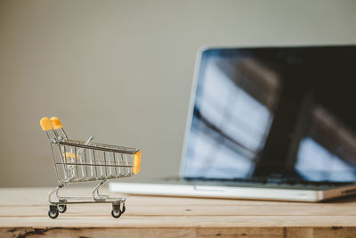 Close-up of shopping cart and laptop on table