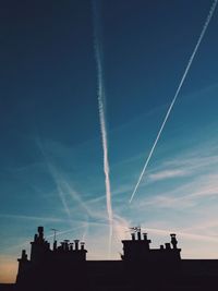 Low angle view of silhouette buildings against blue sky