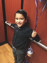 Portrait of smiling boy holding ribbon in elevator